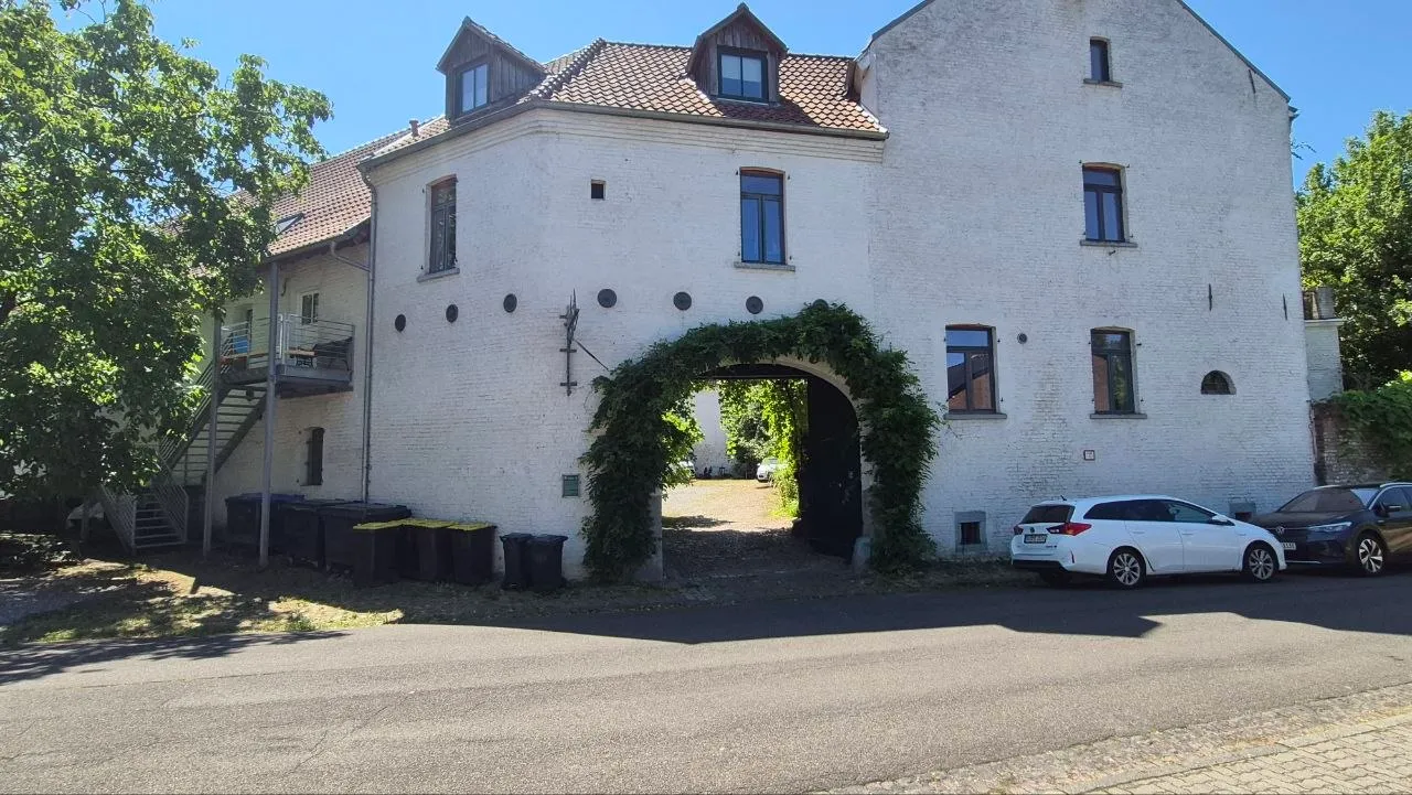 Historischer Bauernhof von der Straße mit begrüntem Torbogen zum Innenhof