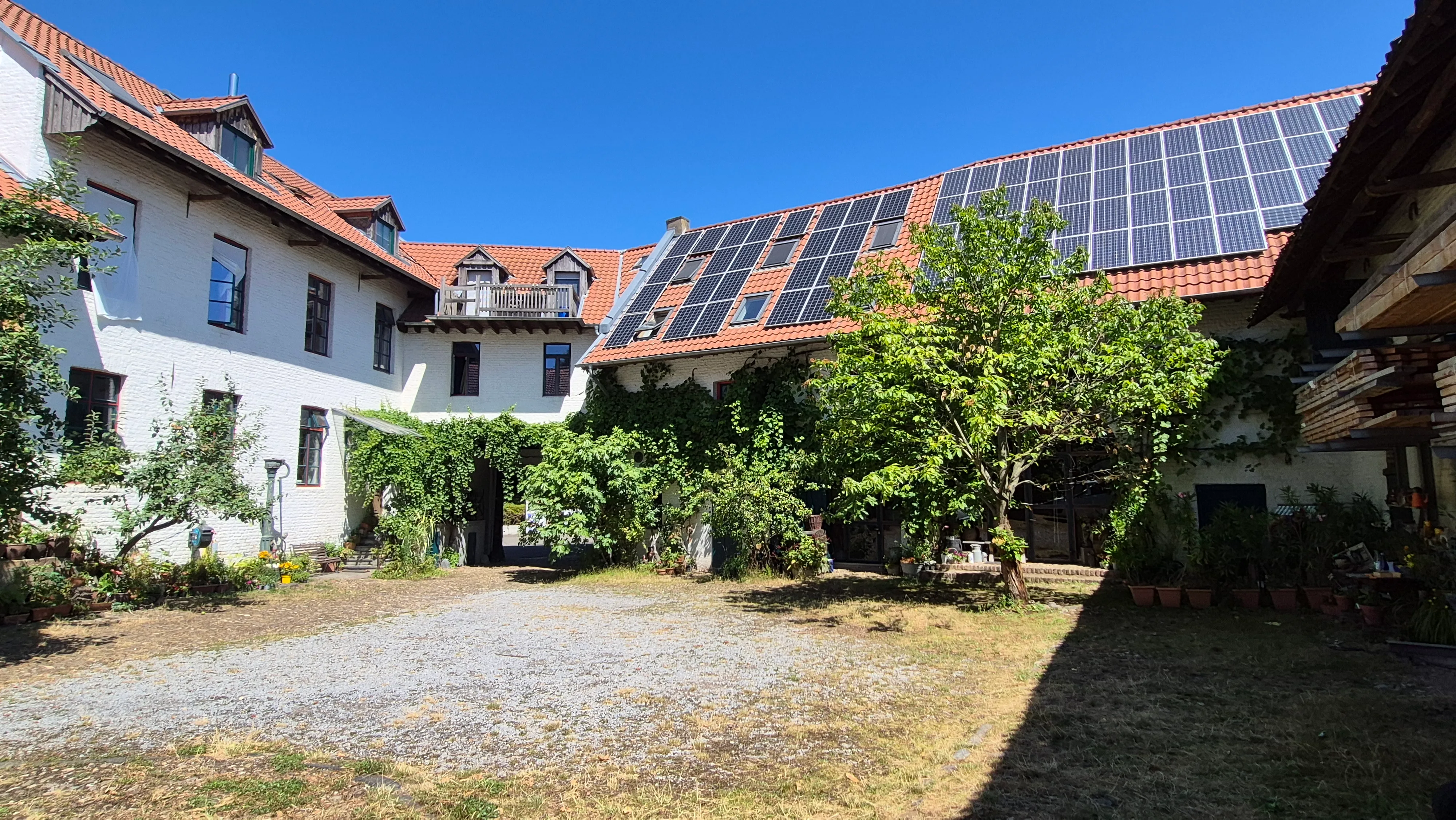 Weitläufiger Innenhof des historischen Bauernhofs Baesweiler mit Solardach
