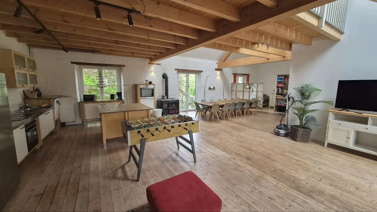 Große offene Wohnküche mit langer Tafel, Galerie und Kaminofen