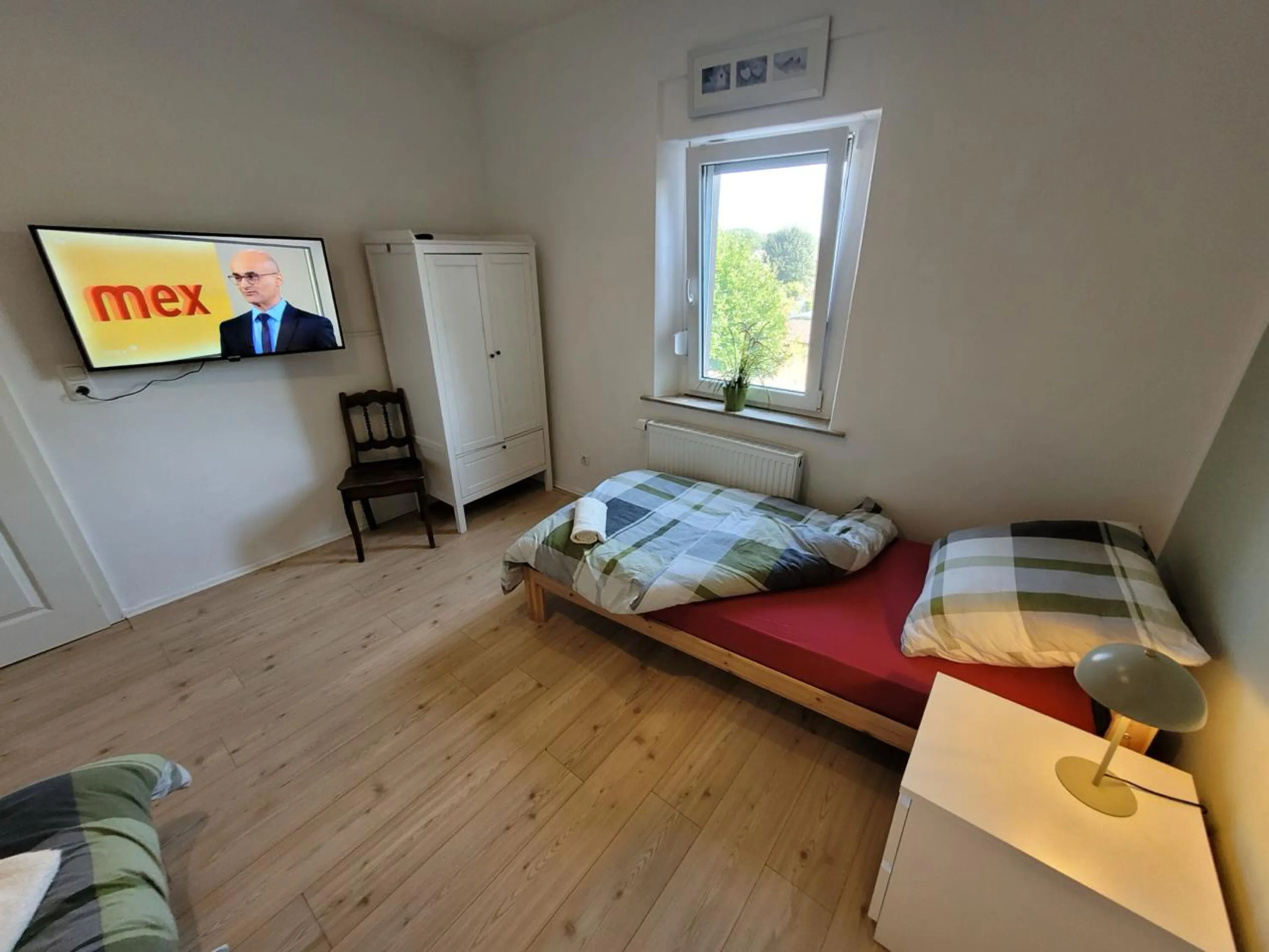 Helles Schlafzimmer mit Einzelbett und Wand-TV